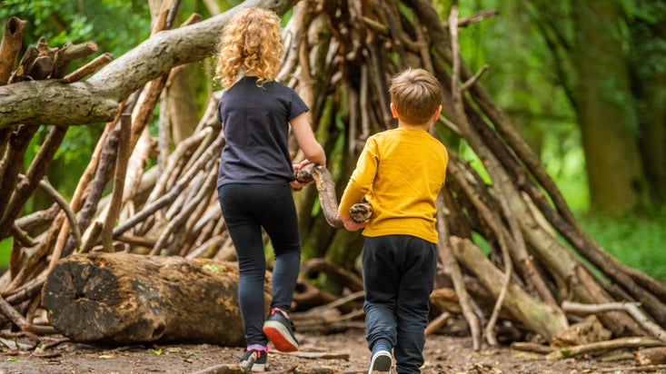 A boy and a girl building a den in woodland